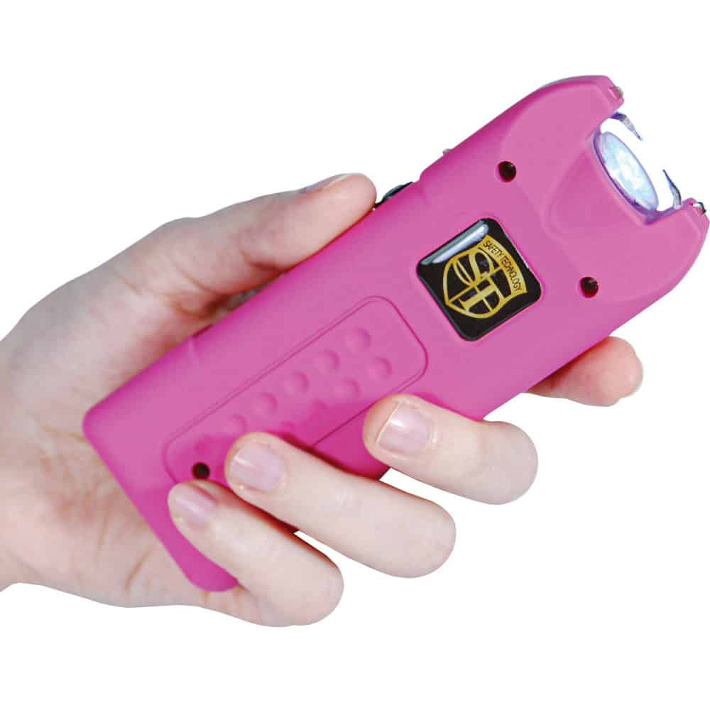 Hand holding a pink stun gun with a safety switch, ideal for self-defense and personal protection.